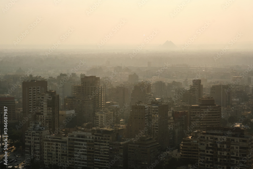 Residential buildings of Cairo and Pyramids of Giza in a haze at background as seen from Cairo TV Tower. Western Cairo and Giza cityscape Residential buildings of Cairo and Pyramids of Giza in a haze at background as seen from Cairo TV Tower. Western Cairo and Giza cityscape