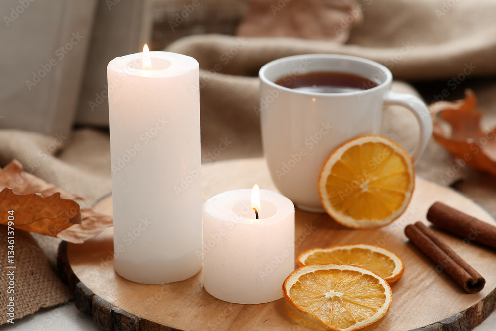 Φωτογραφία Wooden tray with burning candles, cup of tea and dried orange slices near window