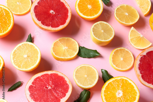 Fototapeta Naklejka Na Ścianę i Meble -  Different cut citrus fruits and leaves on pink background