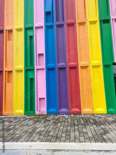 A vibrant close-up of stacked, colorful plastic crates or trays in a row. Abstract pattern of rainbow hues