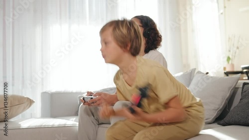 Side view of two teenage boys 15 and 12 emotionally playing video games. Their faces show excitement and focus as they grip controllers fully immersed in the game. Mid range shot side angle