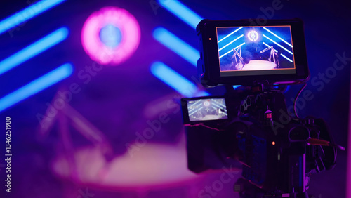 Behind the video camera of podcast set in dark blue neon tube studio LIVE ON AIR