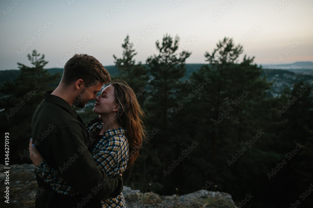 Fototapeta premium Beautiful young woman in the arms of her boyfriend at sunset in the mountains.