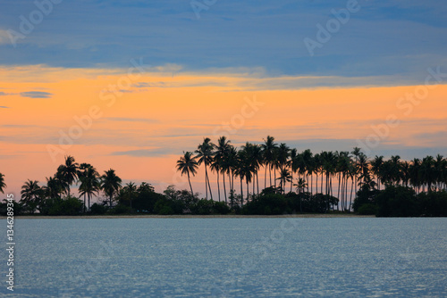 Sunset over the ocean with palm trees line on the Koh Yao Yai island in Thailand