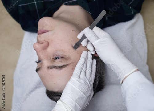 A dermatologist takes a skin scraping test for demodicosis and dermatitis, fungal infection. Close-up of a male patient's face at a doctor's appointment