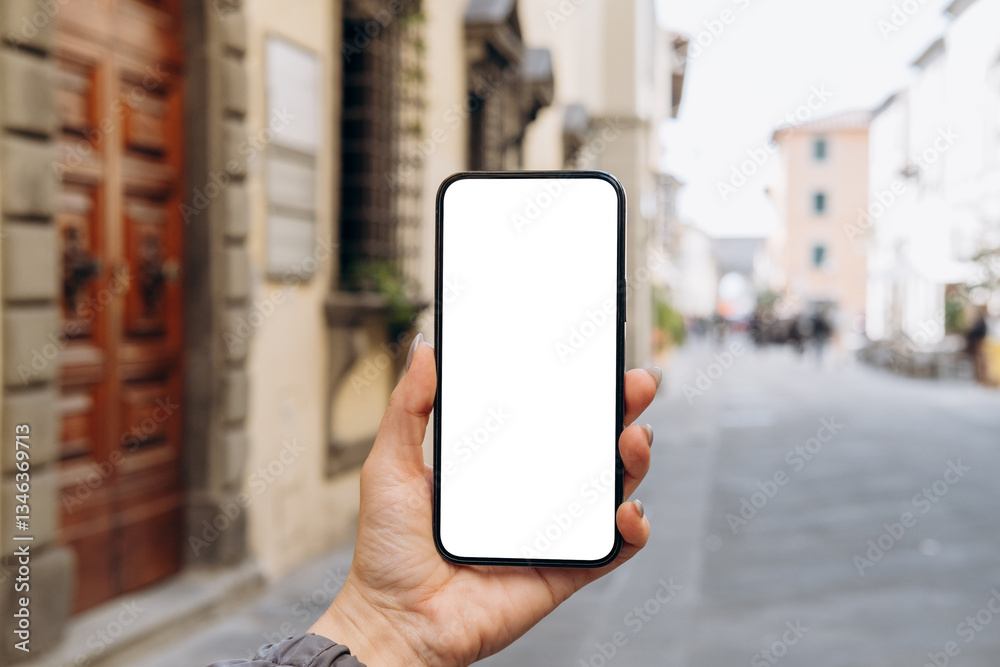 Mockup woman's hand holding using smart phone with white blank screen POV at on the background of a house on the street in Europe real estate rent, mobile app design and advertising, online marketing Mockup woman's hand holding using smart phone with white blank screen POV at on the background of a house on the street in Europe real estate rent, mobile app design and advertising, online marketing