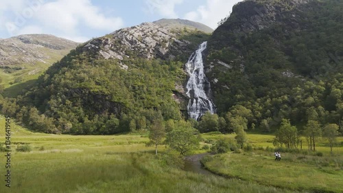 Aerial drone views capture Steall Falls plunging from rugged Highland cliffs into the valley below. A breathtaking sight of raw nature, surrounded by lush greenery and dramatic mountain landscapes
