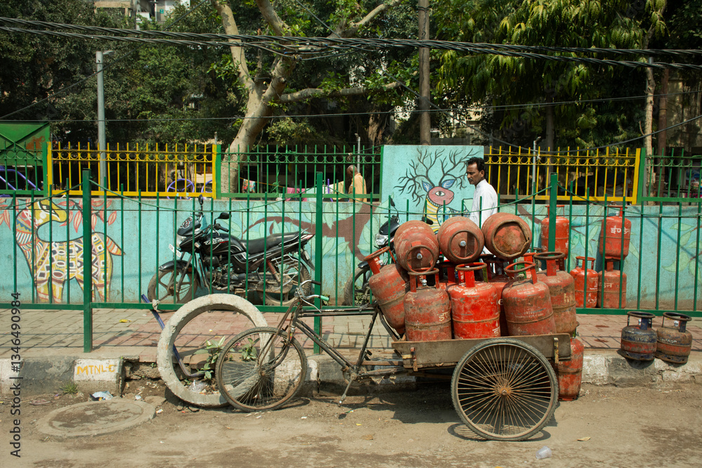 Fototapeta premium Indian and foreign people worker bike bicycle and use tricycle carrying and delivery gas product on the road of rural at Delhi city in New Delhi, India