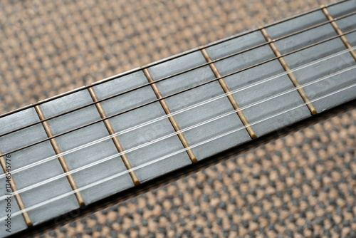 Macro closeup of a guitar fretboard with steel and nylon strings, detailed view of frets up close, musical instrument build details concept, stringed instrument craftsmanship acoustic sound production