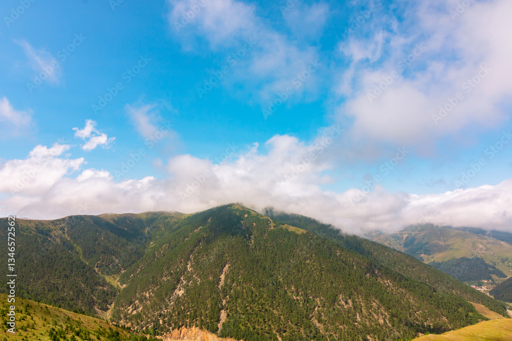 Fototapeta premium Clouds over the forest covered mountains in the summer