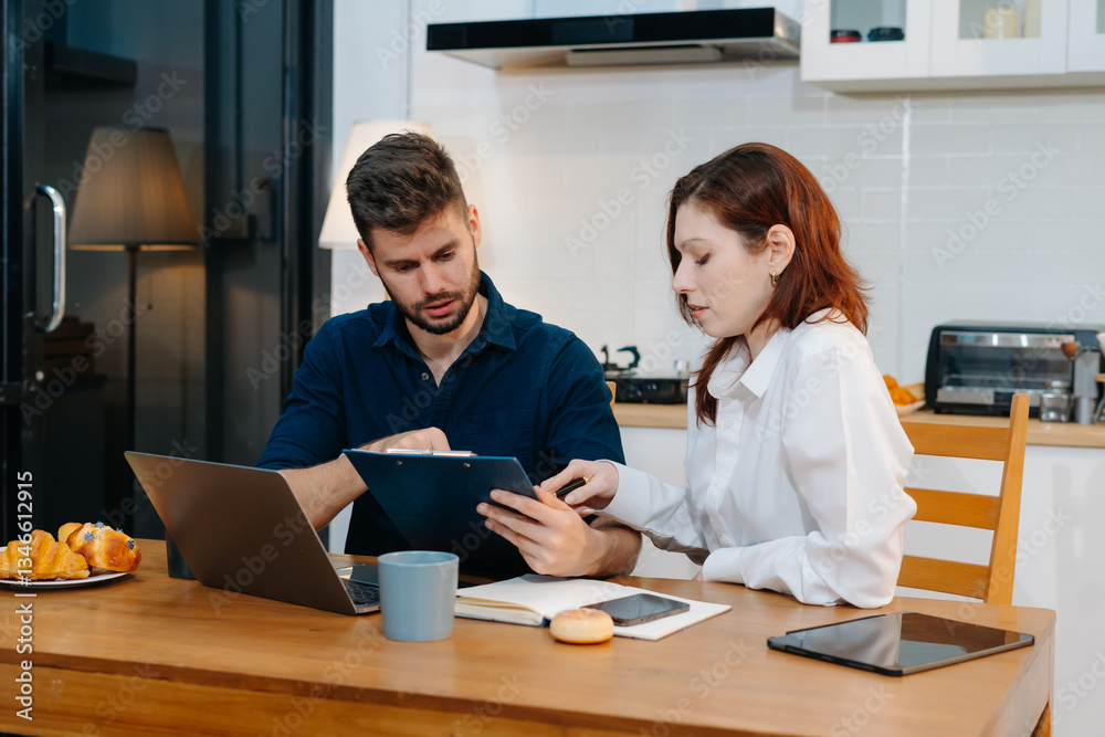 Diverse business team, entrepreneur working online from home, managing documents and laptop at kitchen desk. Diverse business team, entrepreneur working online from home, managing documents and laptop at kitchen desk.