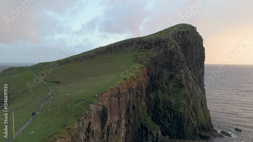 Aerial drone views of Neist Point capture its cliffs and lighthouse at sunset, with a stunning rainbow arching over the ocean. A breathtaking scene, where nature’s beauty meets pure magic. Feelings.