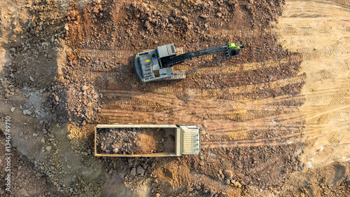 Obraz na płótnie Excavator digs move earth at construction site, Excavator working and digging at construction site, Crawler excavator digger earth gravel on transportation truck at construction site, Top view.. w salonie