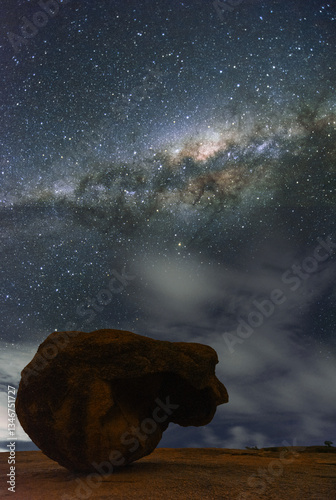Wielki głaz na tle nocnego nieba pełnego gwiazd wraz z  centrum naszej galaktyki 