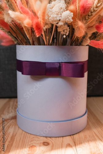 Obraz na płótnie Hat box with purple bow and dried flowers.