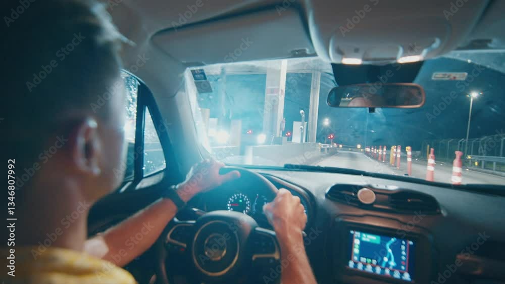 Pay for road with transponder. Adult man steers the car on a toll road during night and quickly passes the payment gate by using a transponder