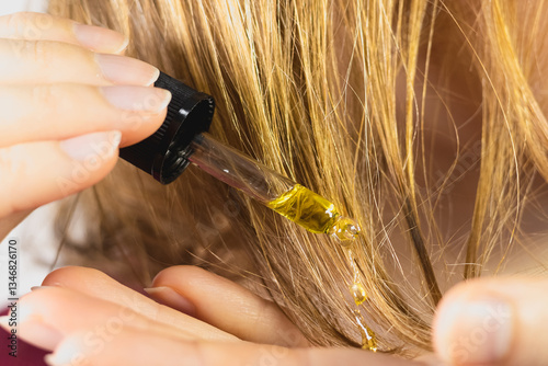 Woman apply moisturizing oil for better hair growth on the head. Hair loss problem. Close up.