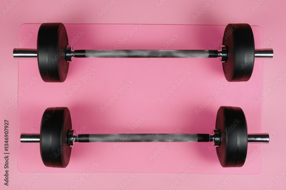 There are two dumbs on a pink surface with a pink background There are two dumbs on a pink surface with a pink background