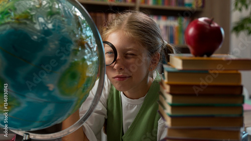 Curious funny adorable intelligent Caucasian little girl playful schoolgirl child school kid pupil learner student looking globe through magnifying glass studying education world map exploring indoor