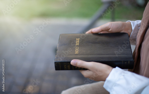 A young woman prays to God while holding a Bible that heals her life. Faith, belief, God concept.
