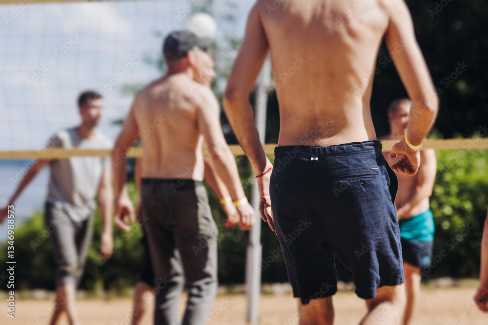 Obraz premium Beach volleyball game, team of adult friends athletes play volleyball by the sea, players on the outdoor playground with net, white sand court field, sports team during the game, in a summer sunny day