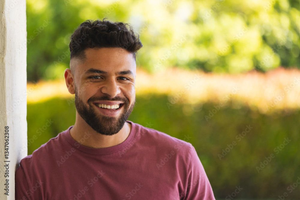 Smiling man enjoying sunny day outdoors, leaning against wall in casual attire, copy space