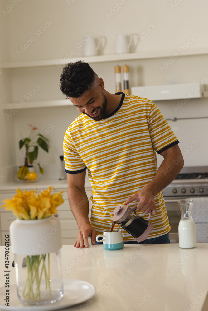Smiling man in striped shirt pouring coffee in modern kitchen at home Smiling man in striped shirt pouring coffee in modern kitchen at home