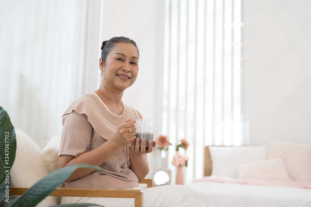 Senior elderly Asian woman drinking tea or coffee at home. Retirement, health care and ageing concept Senior elderly Asian woman drinking tea or coffee at home. Retirement, health care and ageing concept
