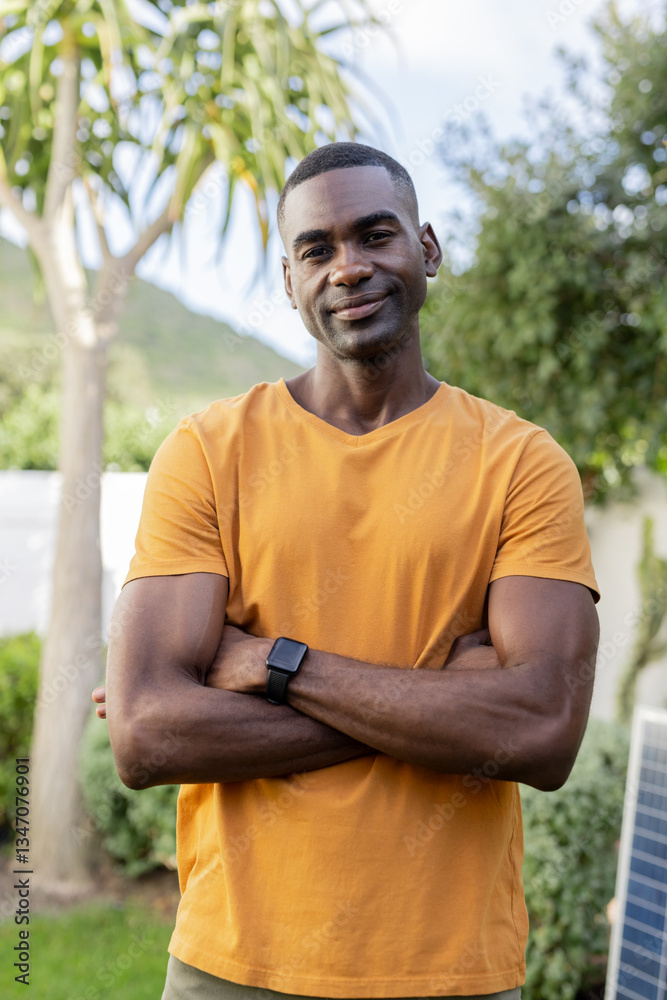 Smiling man in orange shirt standing confidently in sunny garden