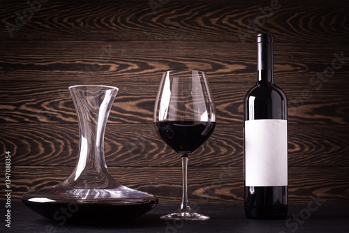 Decanter, glass and bottle with red wine on wooden rustic background