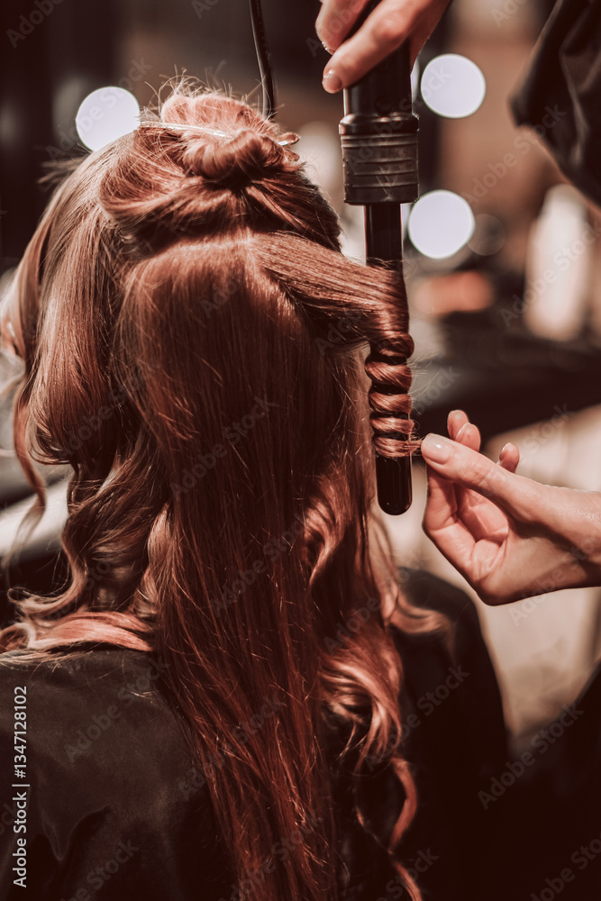 Fototapeta premium Female hands of a stylist doing a hairstyle of a young fashion model, back view