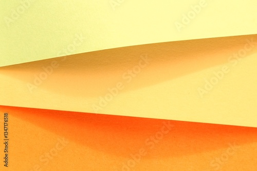Layers of yellow and orange paper. Abstract background of colored paper sheet. Overlapping sheets of different yellow tones. Close-up of folded paper. Textured surface of yellow and orange paper