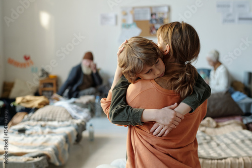 фотографія Rear view of young single mother holding her youthful son on hands while sad boy