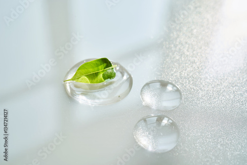 Drop of face serum with green leaf on white background.