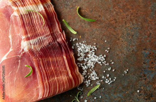 Sliced prosciutto and rosemary on a brown rusty background. photo