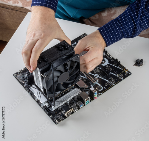 Obraz na płótnie the hands of a man installing a fan on the CPU cooler tower on the motherboard w salonie