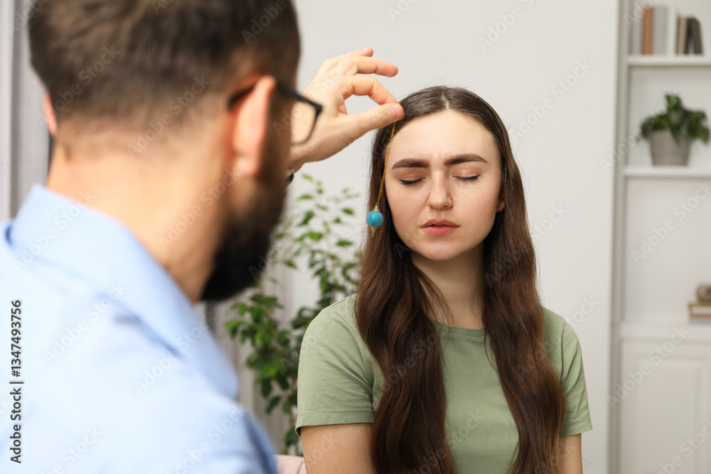 Psychologist using pendulum while working with patient during hypnosis session indoors Psychologist using pendulum while working with patient during hypnosis session indoors