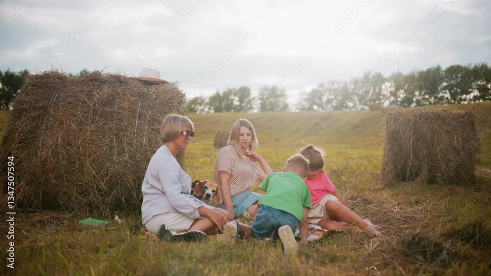 Happy family gathered on checkered blanket in open countryside, enjoying outdoor picnic with snacks, sunlight casts warm glow, with hay bales and trees in background Happy family gathered on checkered blanket in open countryside, enjoying outdoor picnic with snacks, sunlight casts warm glow, with hay bales and trees in background