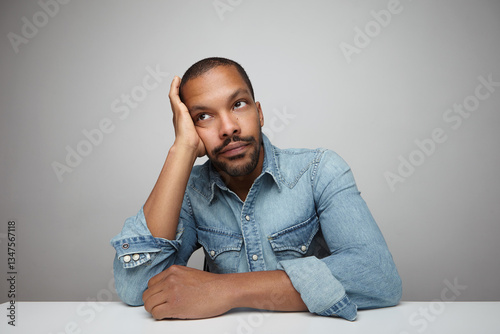 Portrait of bored African American young man posing over white background.