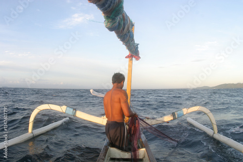 Balinese fisherman fishing in the open water off the shores of Padangbai, Bali.
