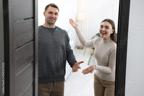Fotografi Happy couple welcoming guests to their apartment