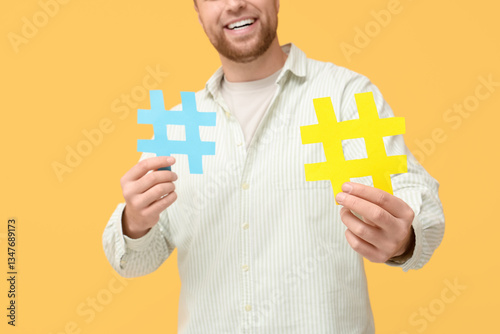 Man with hashtag signs on yellow background, closeup