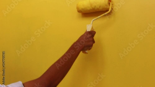 Wall painting activity or painting the wall with yellow color using paint roller. Concept of self-repair and home construction concept. photo