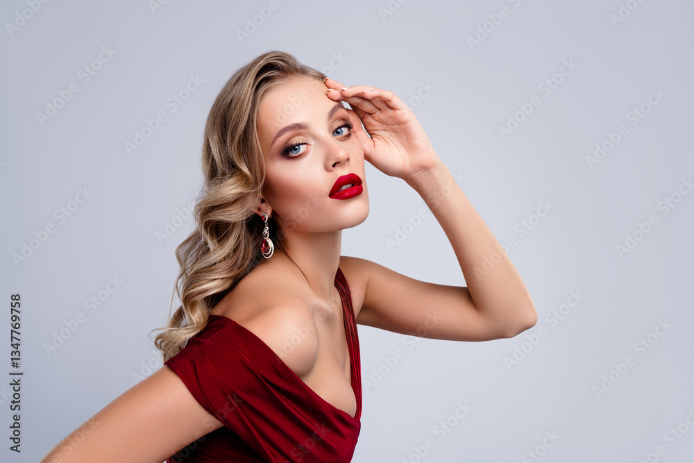 Stunning lady touch face skin posing for photographing wear red dress on grey color background Stunning lady touch face skin posing for photographing wear red dress on grey color background