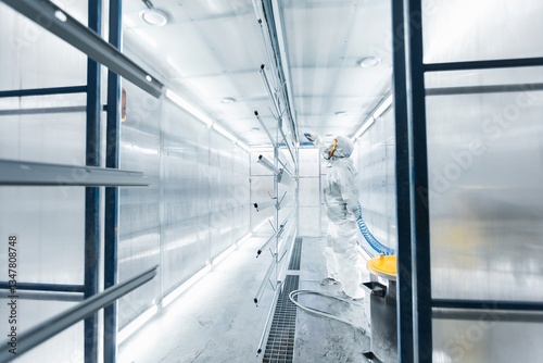 man painting parts in powder coating booth