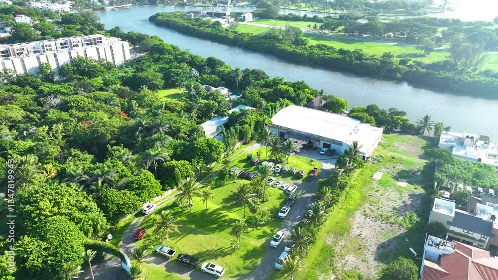 Vista aérea de un salón de eventos en medio de vegetación tropical cerca de un rio 