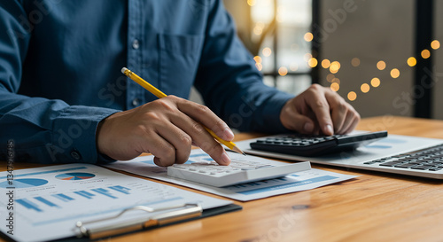 Close-up of a person using a calculator and reviewing financial documents with charts, symbolizing budgeting, financial analysis, business planning, and decision-making in finance.

