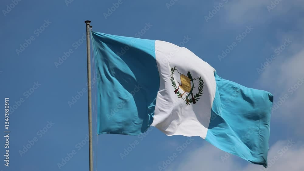 guatemala flag waving in the breeze above a historic colonial building in antigua (guatemalan blue and white flag with quetzal bird) blue sky latin america footage close up