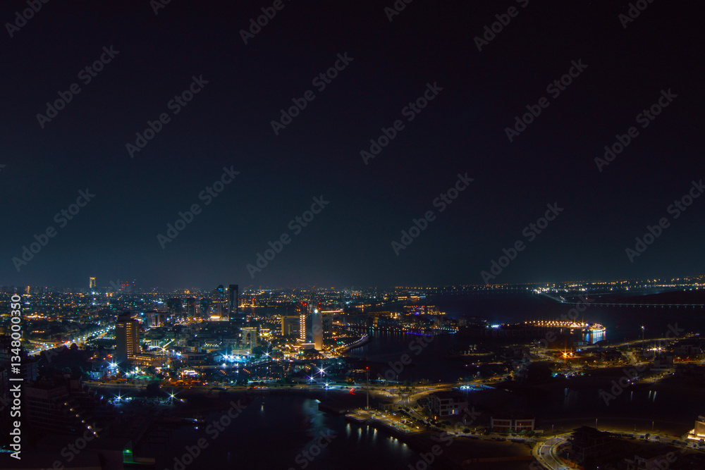 Aerial view of Abu Dhabi at night, showcasing the city's illuminated skyline, modern skyscrapers, and roads glowing under the night sky. Aerial view of Abu Dhabi at night, showcasing the city's illuminated skyline, modern skyscrapers, and roads glowing under the night sky.