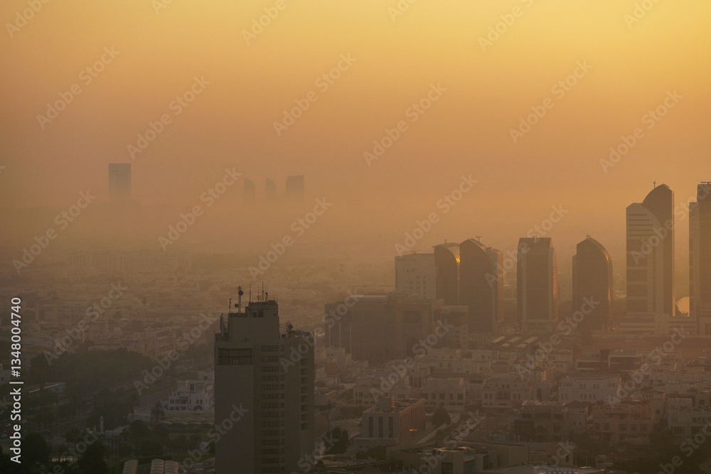 Fototapeta premium Aerial view of Abu Dhabi in the morning light, as the rising sun casts a golden glow over the city's modern skyline.